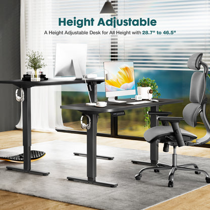 Height adjustable desk with office setup in a room with large windows.