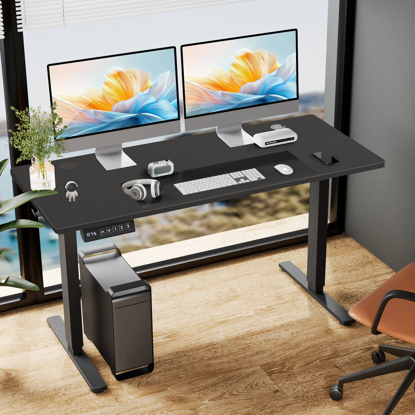 Black computer height adjustable  desk with two monitors, keyboard, and mouse in a room with large windows.
